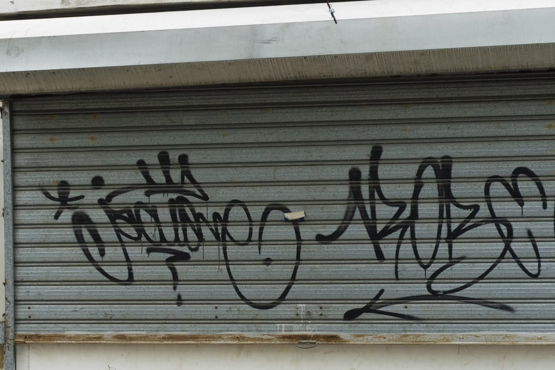 Graffiti tags sprayed across a metal shop shutter