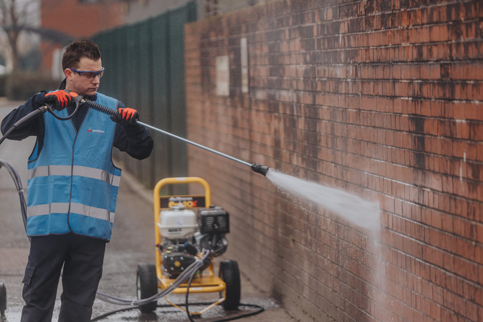 TagBadger operative pressure-washing graffiti off a brick wall